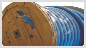 A wooden cable drum wound with blue cable, the cut end capped and strapped flat against the inside face of the drum cheek.